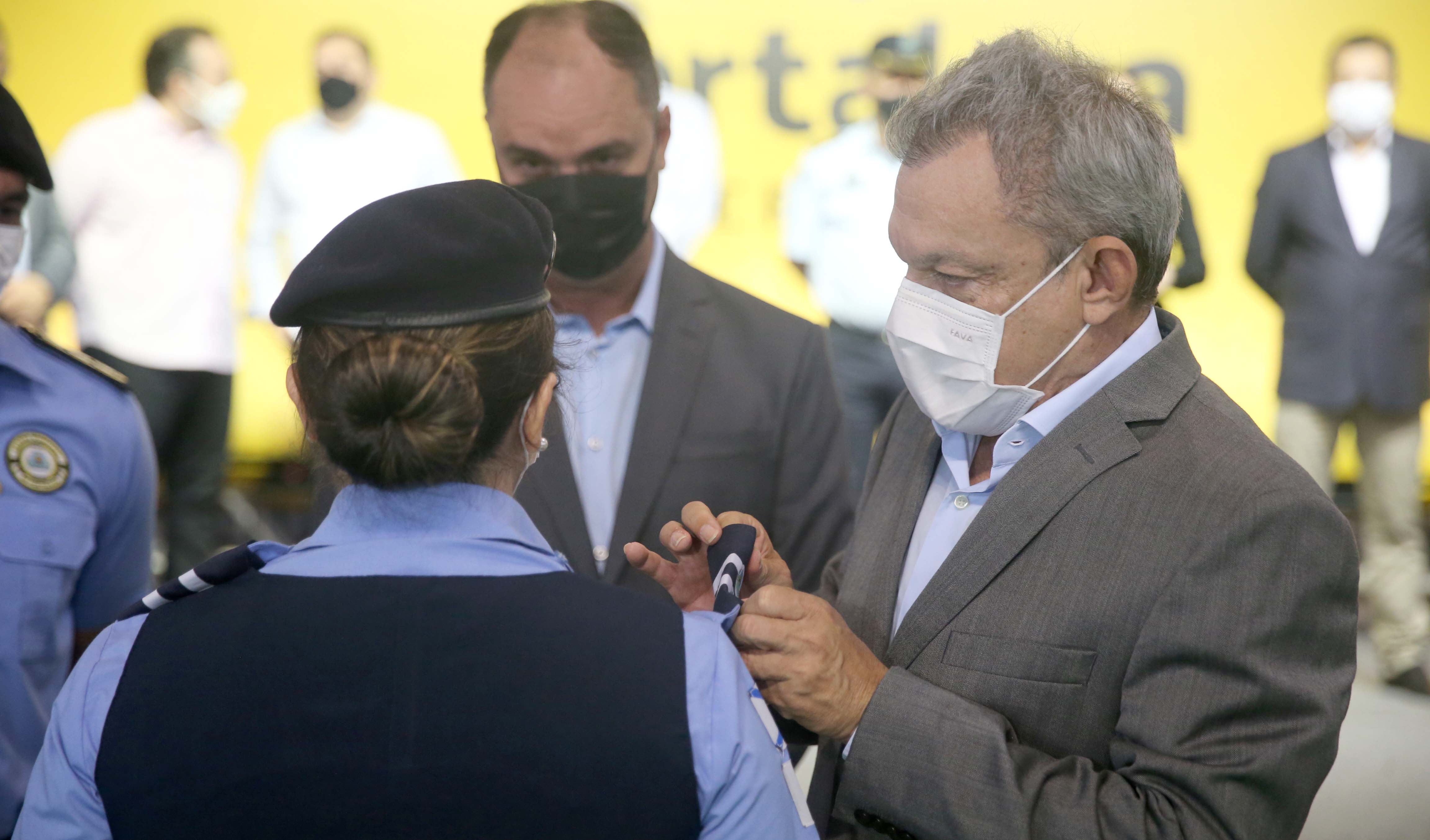 prefeito coloca a insignia no braço de uma guarda municipal